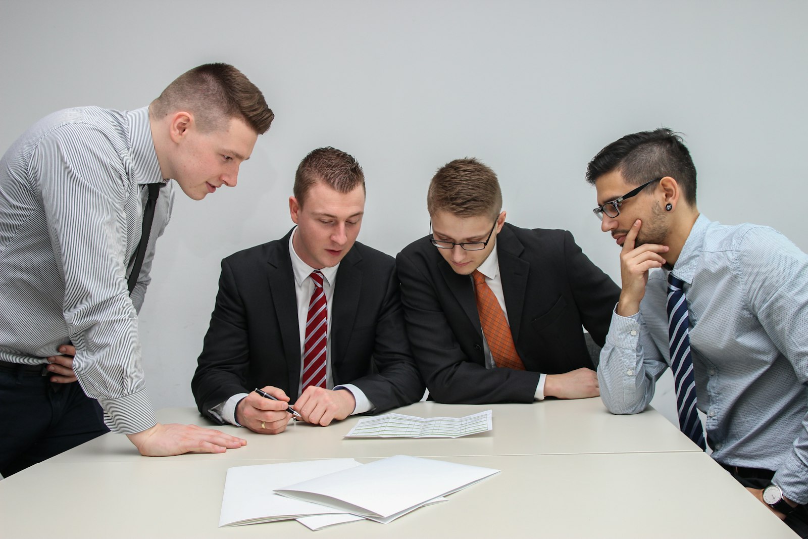 Four people looking at paper on a table